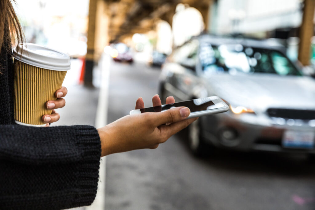 Person holding phone out waiting for rideshare pickup